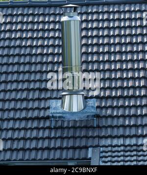 Un camino in acciaio inossidabile coperto nelle tegole di fondo del tetto. Spazio di copia per il testo. Foto Stock