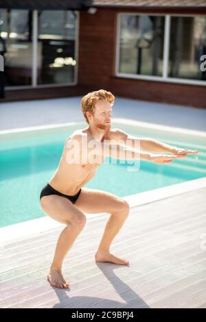 Attraente giovane uomo che fa sport vicino alla piscina Foto Stock