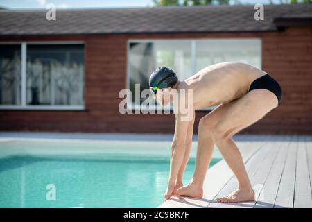 Uomo in profilo presso la piscina prima di immergersi Foto Stock