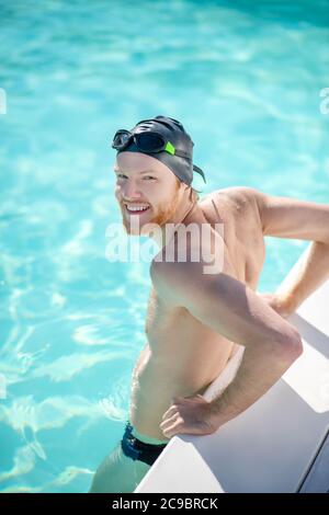 Uomo soddisfatto in piedi in acqua in piscina Foto Stock