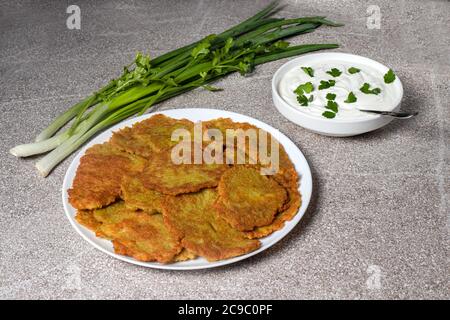 Frittelle di patate su un piatto, servite con panna acida e prezzemolo. Foto Stock