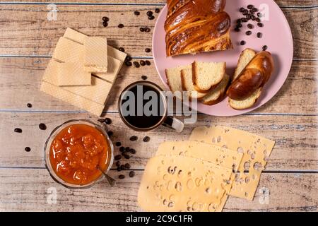 L'idea di una deliziosa colazione per tutta la famiglia. Panino di vimini, formaggio, marmellata di albicocche, waffle e caffè nero aromatico. Layout. Foto Stock