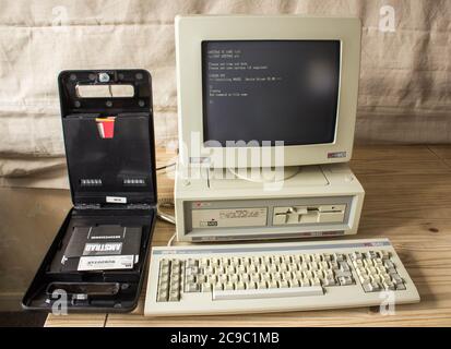 Vintage Amstrad PC1640HD20, computer storico su scrivania con scatola di dischi floppy da 3.5 pollici. Foto Stock