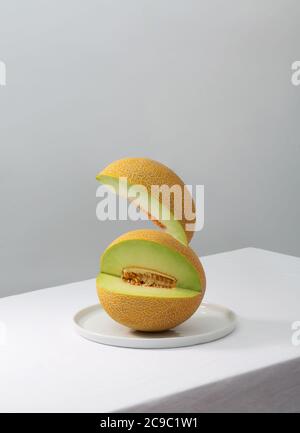 Pezzo di melone tagliato volante su tavolo bianco Foto Stock