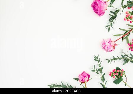 Cornice floreale in peonie rosa e rami di eucalipto su bianco. Disposizione piatta, vista dall'alto Foto Stock