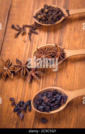 spezie di unghie, anis star e barberry in cucchiai di legno in uno studio Foto Stock