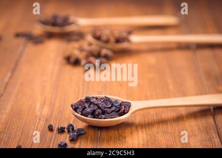 spezie di unghie, anis star e barberry in cucchiai di legno in uno studio Foto Stock