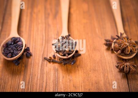 spezie di unghie, anis star e barberry in cucchiai di legno in uno studio Foto Stock