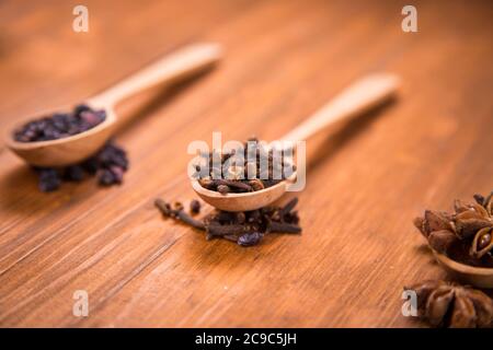 spezie di unghie, anis star e barberry in cucchiai di legno in uno studio Foto Stock