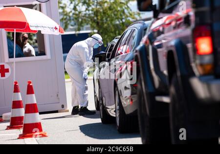 Bergen, Germania. 30 luglio 2020. I dipendenti della Croce Rossa Bavarese si sottoponano a un test di sbavatura presso un centro di prova corona sull'autostrada 8 (A8) nella zona di sosta di Hochfelln-Nord. In considerazione del recente aumento delle cifre relative all'infezione da corona, il governo dello Stato bavarese sta lanciando un'offensiva contro l'incuria e sta lanciando un'offensiva di prova. Le persone che ritornano da un viaggio possono avere essi stessi testato per il virus corona a varie fermate di riposo gratuitamente. Credit: Sven Hoppe/dpa/Alamy Live News Foto Stock