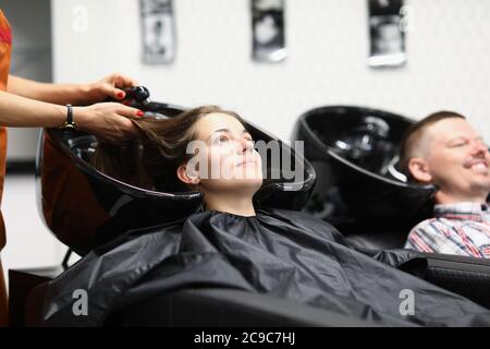 Un impiegato del salone lava i capelli alla donna nel lavandino Foto Stock