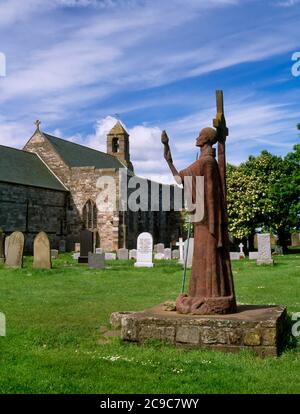 Vista a sud-ovest di una statua in cemento e arenaria rossa di St Aidan, realizzata nel 1958 dalla scultorea Kathleen Parbury, che si trova a St Mary's Churchyard, Holy Island, Regno Unito Foto Stock
