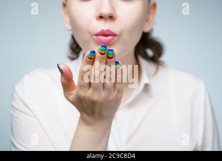 Immagine di donna con manicure arcobaleno che fa bacio d'aria Foto Stock