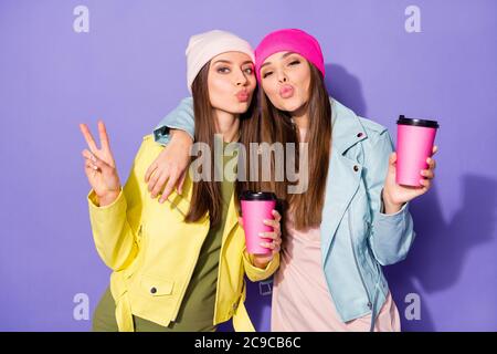 Ritratto di belle ragazze allegre bevendo latte divertendosi mostrare il segno v inviando aria bacio ombra isolato su brillante vivido brillare vibrante Foto Stock