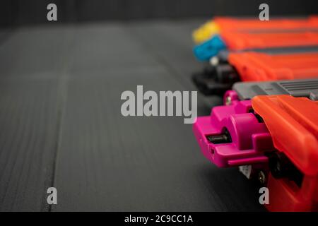 Nuove cartucce di toner per stampanti laser in magenta, nero, giallo e ciano, primo piano, su sfondo grigio in legno Foto Stock