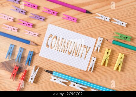 Scrittura a mano concettuale che mostra la Comunità. Concetto significato con una caratteristica comune o interesse che vivono insieme carta sminuzzata colorata Flo di legno Foto Stock