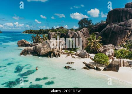 Isola 'la digue' alle Seychelles. Spiaggia argentata con pietra granitica e giungla. Uomo che ama le vacanze in spiaggia e divertirsi con il kayak. Antenna v Foto Stock