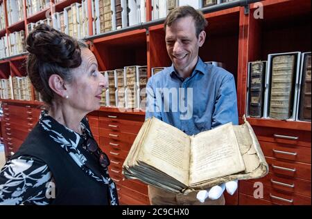 30 luglio 2020, Sassonia-Anhalt, Merseburg: L'artista di Lipsia Antoinette guarda gli incantesimi originali di Merseburg nelle mani di Markus Cottin, capo dell'archivio del monastero della cattedrale e della biblioteca del monastero della cattedrale Merseburg. Le due formule magiche dell'alta Germania antica si trovano in un sacramentale e sono state probabilmente registrate lì nel primo o nel secondo terzo del X secolo. Le formule magiche di Merseburg servono l'artista Antoinette come fonte di ispirazione per la sua opera "altare d'Europa", che sarà creata nel Merseburg Schlossgartensalon fino al novembre 2020 e su cui ha letto Foto Stock