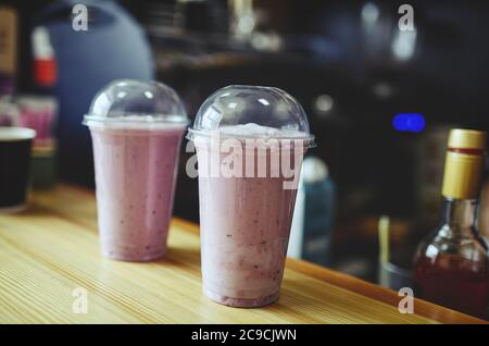 Frullato di fragola coperto in vetro di plastica sul tavolo in cafe.immagine sfocata, fuoco selettivo Foto Stock