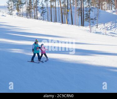 Ekaterinburg, Russia - 26 febbraio 2019. Pista di allenamento del complesso sportivo sul monte Uktus. Un formatore insegna a un bambino a sciare. Foto Stock