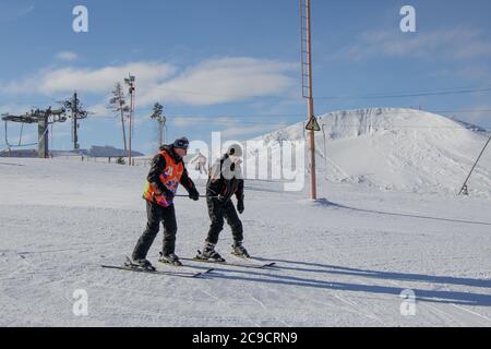 Ekaterinburg, Russia - 26 febbraio 2019. Pista di allenamento del complesso sportivo sul monte Uktus. Un allenatore anziano insegna a sciare un uomo. Foto Stock