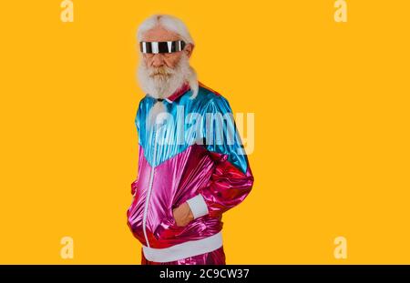 Nonno alla moda in posa con divertenti abiti futuristici. Ritratti dell'uomo anziano su sfondo colorato Foto Stock