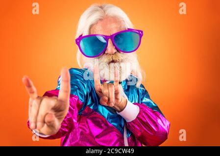 Nonno alla moda in posa con divertenti abiti futuristici. Ritratti dell'uomo anziano su sfondo colorato Foto Stock