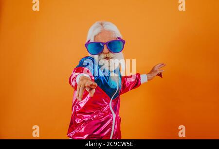 Nonno alla moda in posa con divertenti abiti futuristici. Ritratti dell'uomo anziano su sfondo colorato Foto Stock