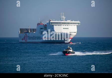 Nave traghetto forza della compagnia Trasmediterránea che entra nel porto di Barcellona preceduta dalla barca pilota. Foto Stock