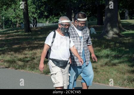 2 uomini asiatici americani si esercitano a piedi in un parco indosso9maschere viso e schermi viso. A Flushing, Queens, New York City Foto Stock