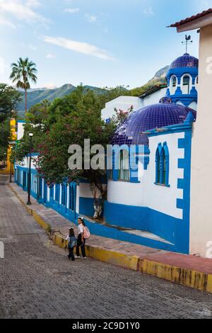 Batacillas, Chihuahua, Messico. Scena della strada di mattina presto, i bambini camminano verso la scuola, l'hotel di Lodge di Riverside sulla destra. Foto Stock