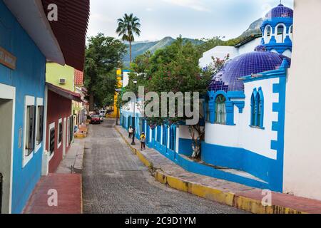 Batacillas, Chihuahua, Messico. Scena della strada di mattina presto, i bambini camminano verso la scuola, l'hotel di Lodge di Riverside sulla destra. Foto Stock