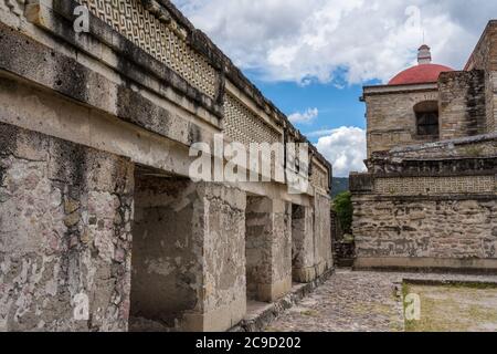 Pannelli in pietra sulle pareti del cortile B, (Quadrangle B), nelle rovine della città Zapotec di Mitla, vicino a Oaxaca, Messico. Dietro c'è la Coira Foto Stock