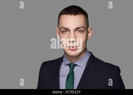 Casualmente bello giovane uomo. Uomo caucasico sicuro e bello in cravatta e vestito su sfondo grigio. Foto Stock
