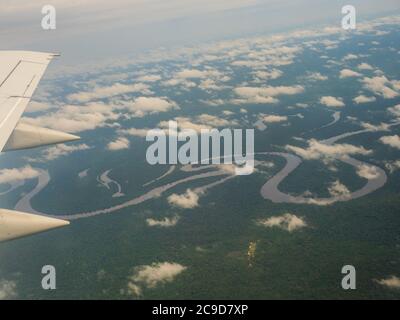 Vista dalla finestra di aereo. Ala di un aeroplano che vola sopra le nuvole oltre il fiume del Amazon. Vista superiore della foresta pluviale amazzonica. Il Perù, Brasile. La Colombia. Foto Stock