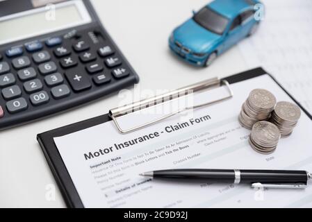 Motore o assicurazione auto claim form con moneta della pila, calcolatrice e modello di auto. Foto Stock