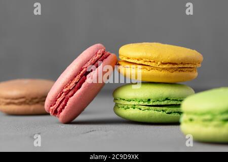 Biscotti macaroon colorati su superficie grigia primo piano Foto Stock