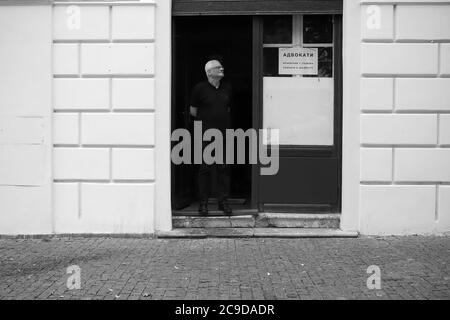 Belgrado, Serbia, 18 giu 2020: Uomo nero in piedi presso la porta dell'ufficio legale (B/N) Foto Stock