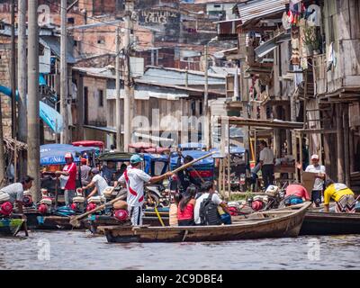 Belen, Perù - dicembre 2019: Persone sulle barche tra case galleggianti nella pianura alluvionale del fiume Itaya, la parte più povera di Iquitos - Belén. Venezia di la Foto Stock