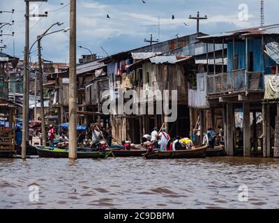 Belen, Perù - dicembre 2019: Persone sulle barche tra case galleggianti nella pianura alluvionale del fiume Itaya, la parte più povera di Iquitos - Belén. Venezia di la Foto Stock