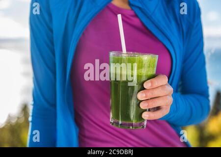 Donna sana che mangia bevendo frullato verde detox Foto Stock