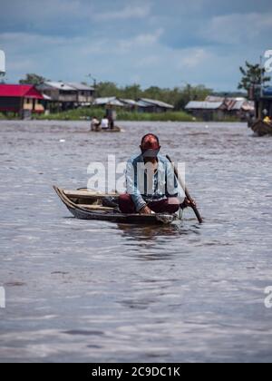 Belen, Perù - Dic 2019: Uomo che pesca dalla piccola barca di legno tra le case nella pianura alluvionale del fiume Itaya, la parte più povera di Iquitos - Belén. V Foto Stock