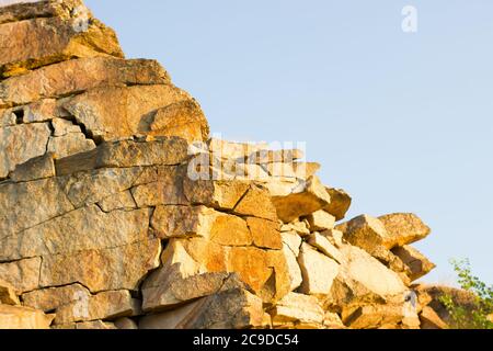 Consistenza di una grande roccia di granito fatta di pietre contro un cielo blu - sfondo di cava di pietra di marmo Foto Stock