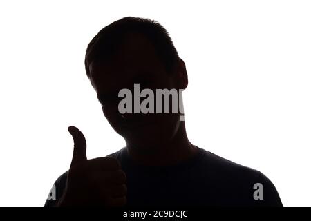 La silhouette sorridente mano di un giovane uomo mostra il simbolo di una silhouette ok - Foto Stock