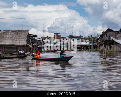 Belen, Perù - dicembre 2019: Persone sulle barche tra case galleggianti nella pianura alluvionale del fiume Itaya, la parte più povera di Iquitos - Belén. Venezia di la Foto Stock