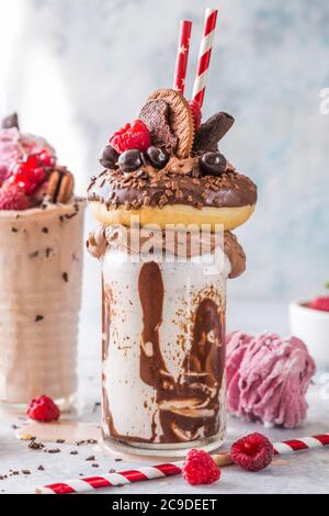 Frullato al cioccolato con frittella e ciambelle. Folle tendenza alimentare freakshake. Spazio di copia Foto Stock