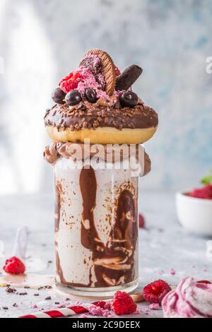 Frullato al cioccolato con frittella e ciambelle. Folle tendenza alimentare freakshake. Spazio di copia Foto Stock