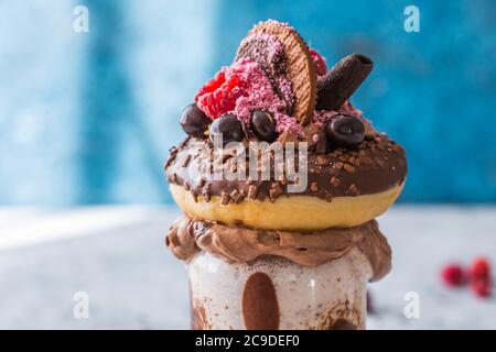Frullato al cioccolato con frittella e ciambelle. Folle tendenza alimentare freakshake. Spazio di copia Foto Stock
