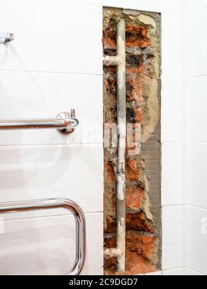 riparazione del collettore idraulico di scaldasalviette a casa - vecchio tubo di alimentazione dell'acqua in parete rotta Foto Stock