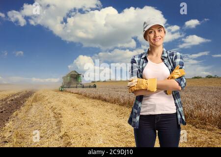 Lavoratore femminile in un campo di grano e una mietitrebbia nella parte posteriore Foto Stock